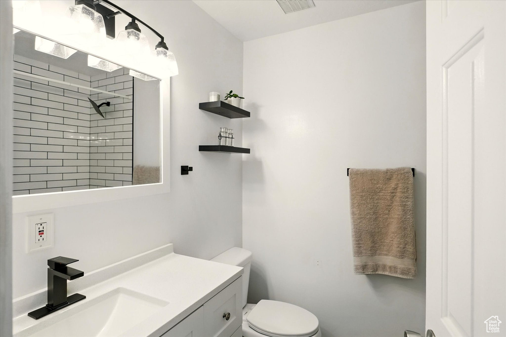Full bath with toilet, a tile shower, and vanity