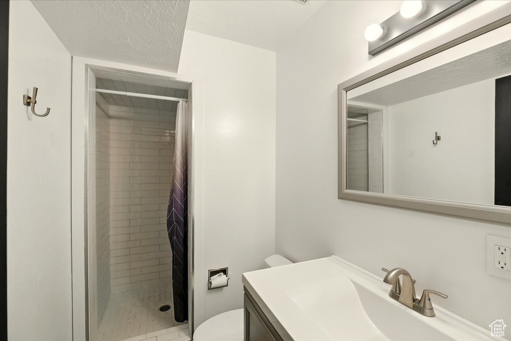 Bathroom featuring toilet, a shower stall, and vanity