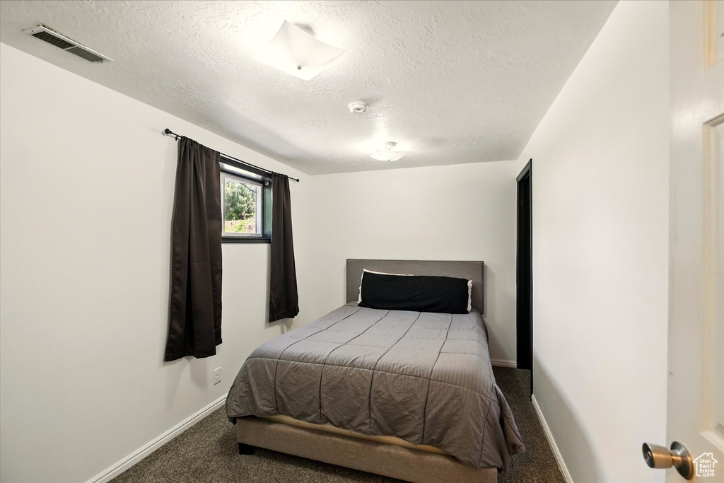 Bedroom with carpet floors, a textured ceiling, and baseboards