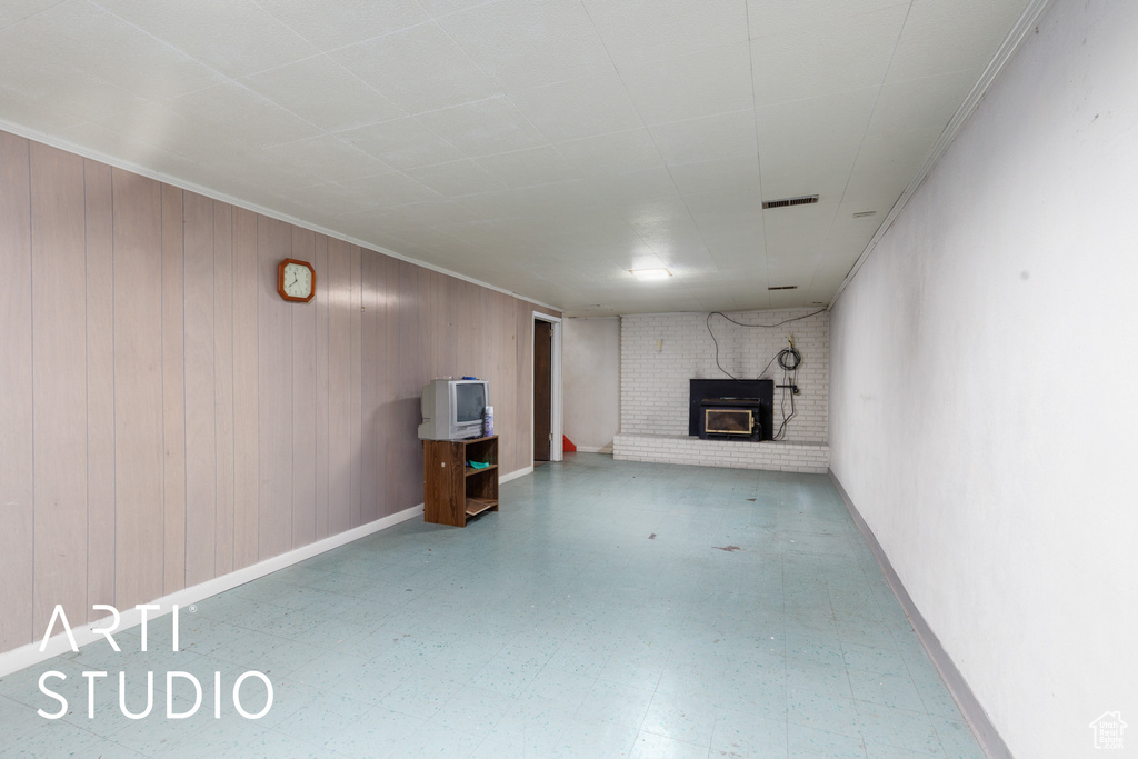 Finished basement with a brick fireplace, tile patterned floors, and wooden walls