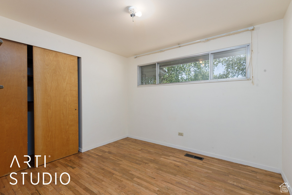 Unfurnished bedroom featuring wood finished floors, a closet, and baseboards