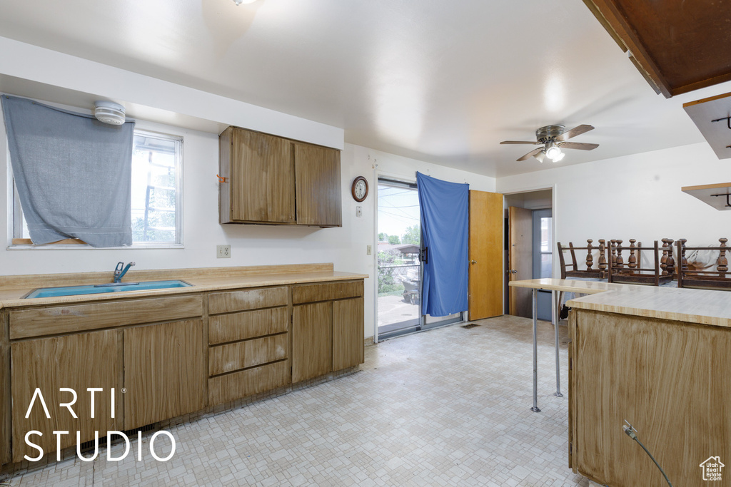 Kitchen featuring a sink, light flooring, a ceiling fan, and light countertops