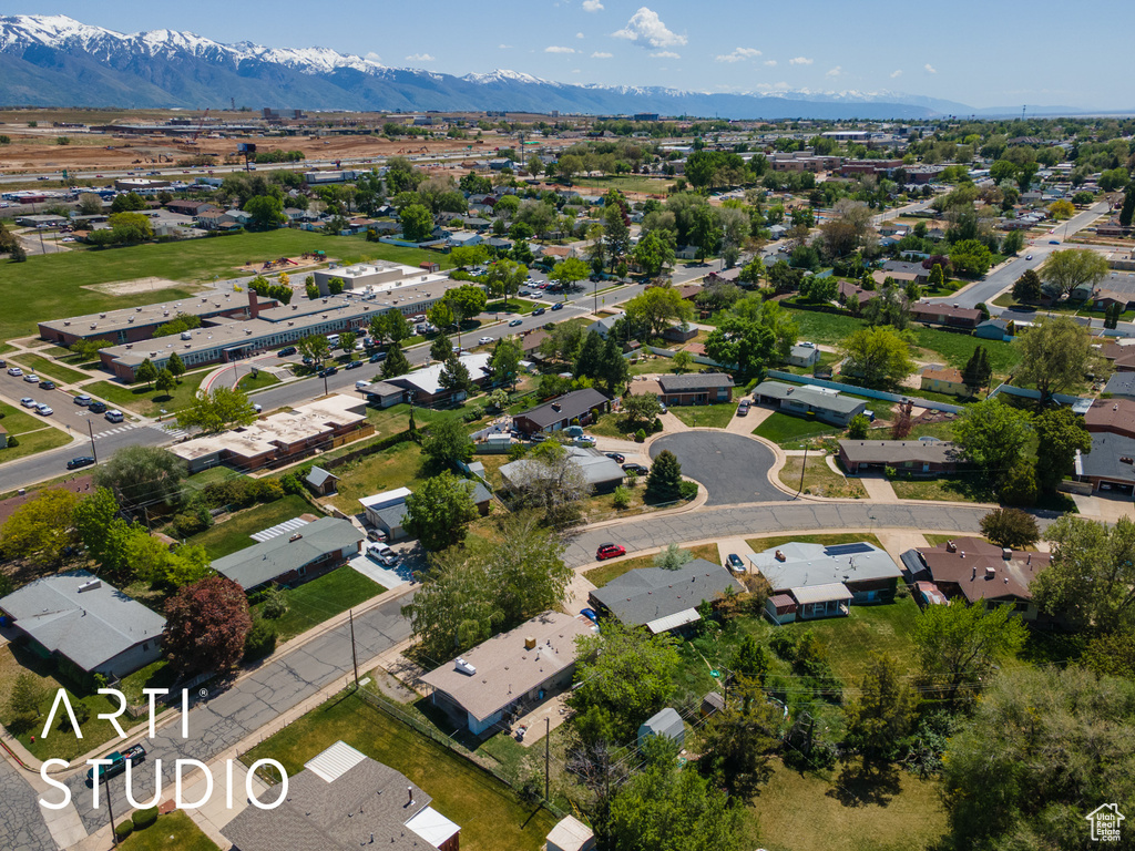 Aerial view of property and surrounding area with a mountainous background and nearby suburban area