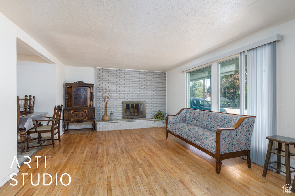 Living room featuring light wood-style flooring, a fireplace, and a textured ceiling