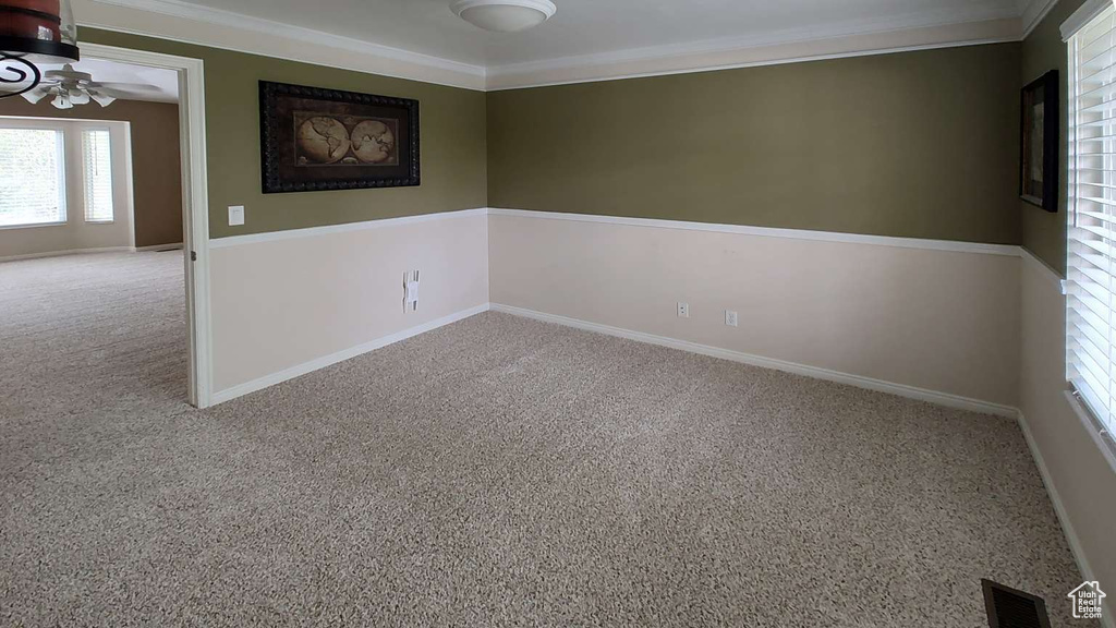 Unfurnished room featuring a ceiling fan, crown molding, carpet floors, and baseboards