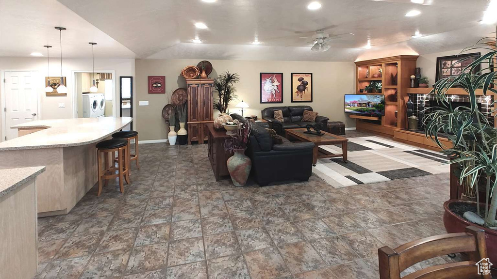 Living room with washer / dryer, recessed lighting, baseboards, stone finish flooring, and a ceiling fan
