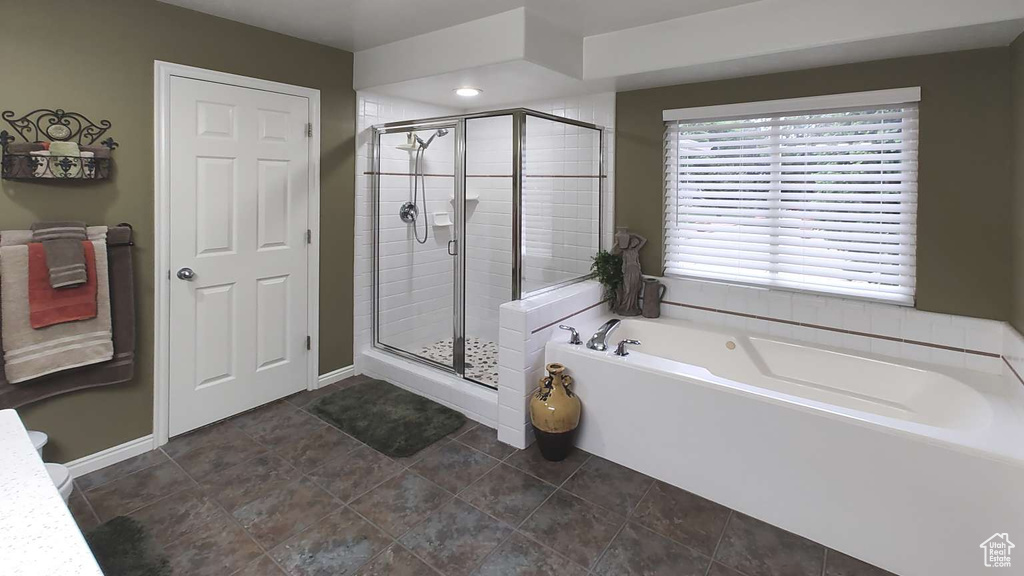 Full bath with a shower stall, a garden tub, and baseboards