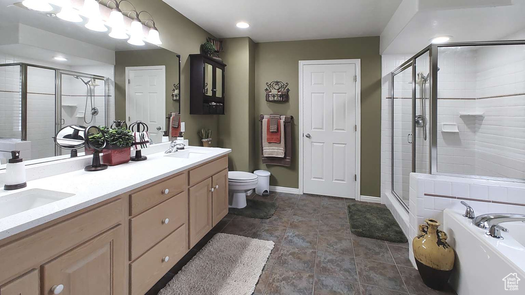 Bathroom with a stall shower, a bath, baseboards, double vanity, and toilet