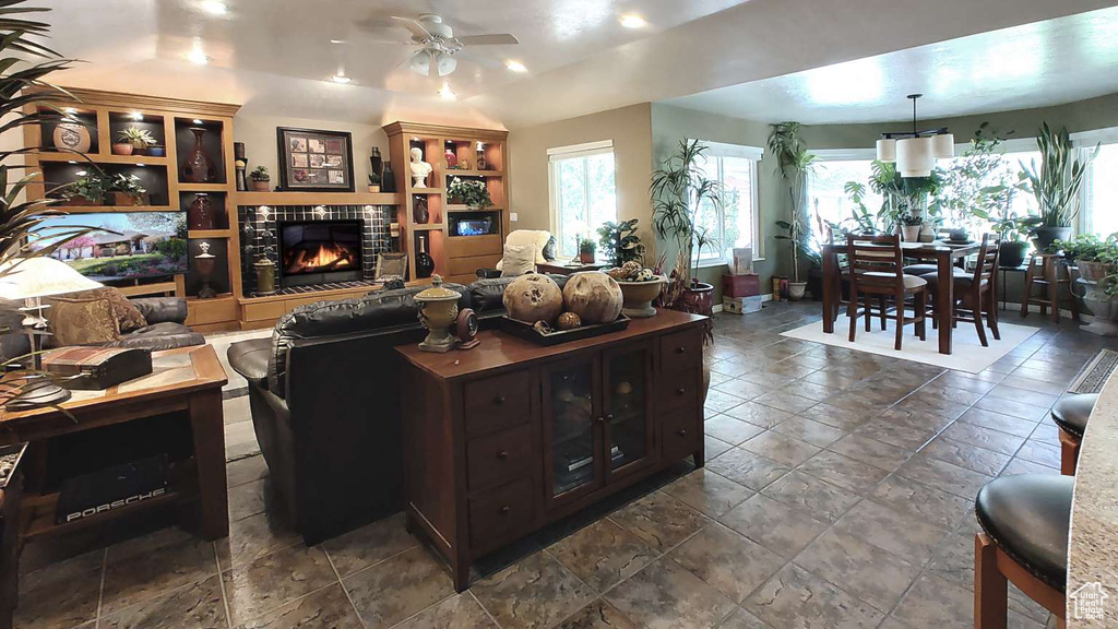 Living room with a ceiling fan, a fireplace, stone tile floors, and recessed lighting