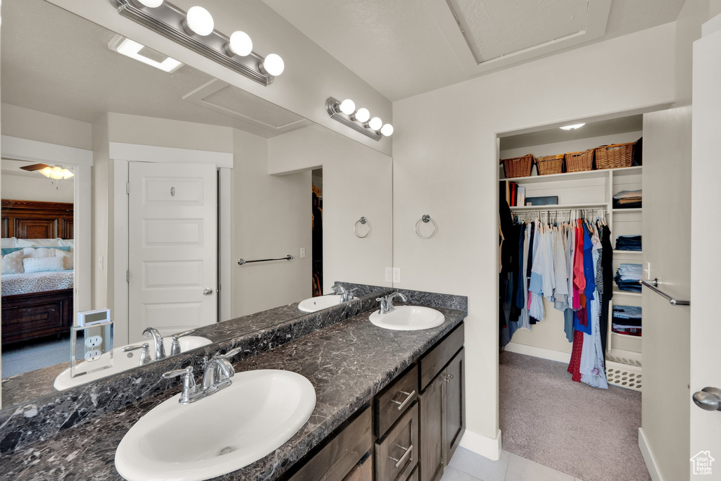 Full bath with ensuite bath, baseboards, double vanity, and a walk in closet