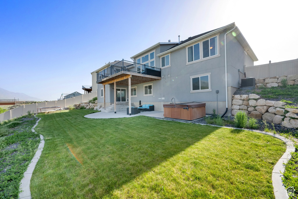 Rear view of property with a hot tub, central AC, a patio area, stucco siding, and a deck