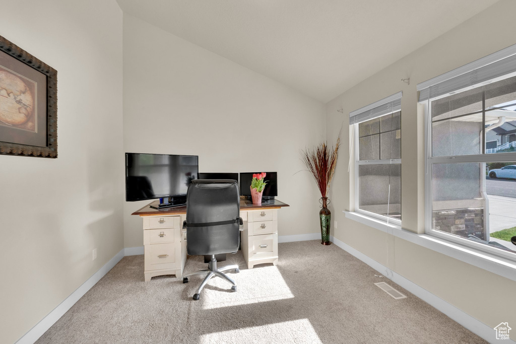 Office space with vaulted ceiling, plenty of natural light, light carpet, and baseboards