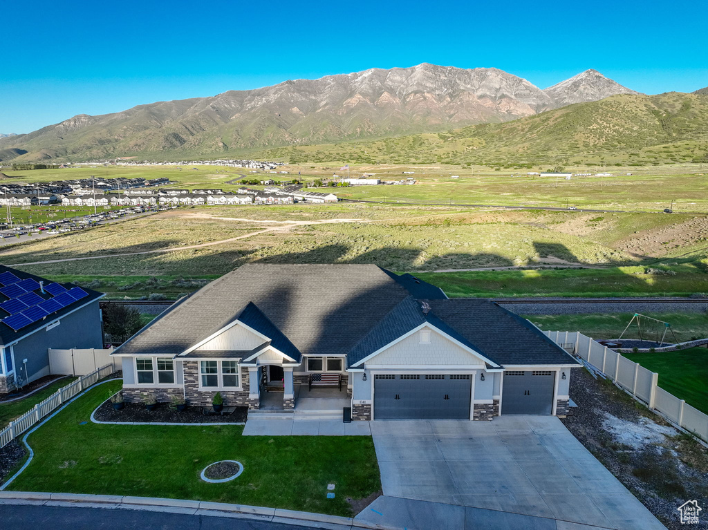View of front of property with stone siding, an attached garage, concrete driveway, and a mountain view