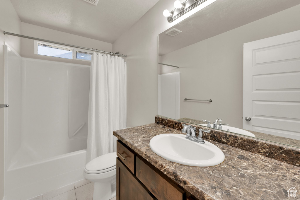 Bathroom featuring toilet, vanity, shower / tub combo with curtain, and tile patterned floors