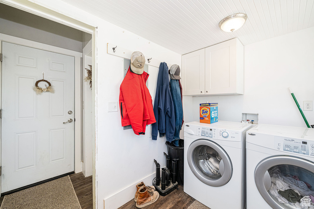 Washroom featuring dark wood-style floors, washing machine and clothes dryer, cabinet space, and baseboards