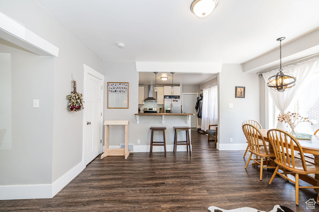 Dining area featuring dark wood-type flooring, baseboards, and a chandelier
