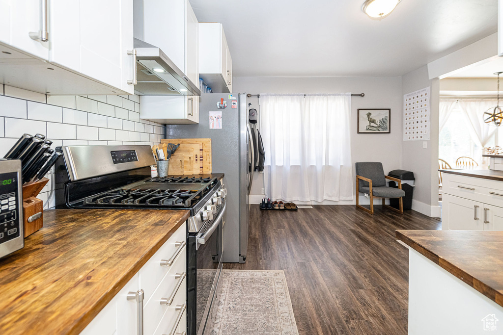 Kitchen with wood counters, stainless steel gas range oven, healthy amount of natural light, and wall chimney exhaust hood