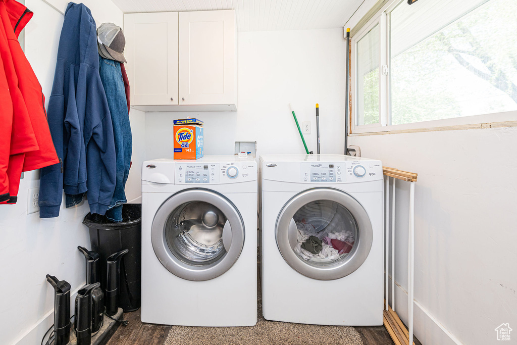 Washroom featuring washer and dryer, wood finished floors, and cabinet space