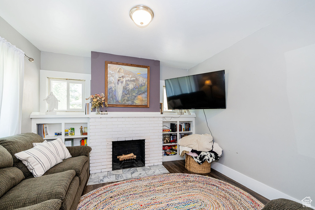Living area with wood finished floors, a brick fireplace, and baseboards