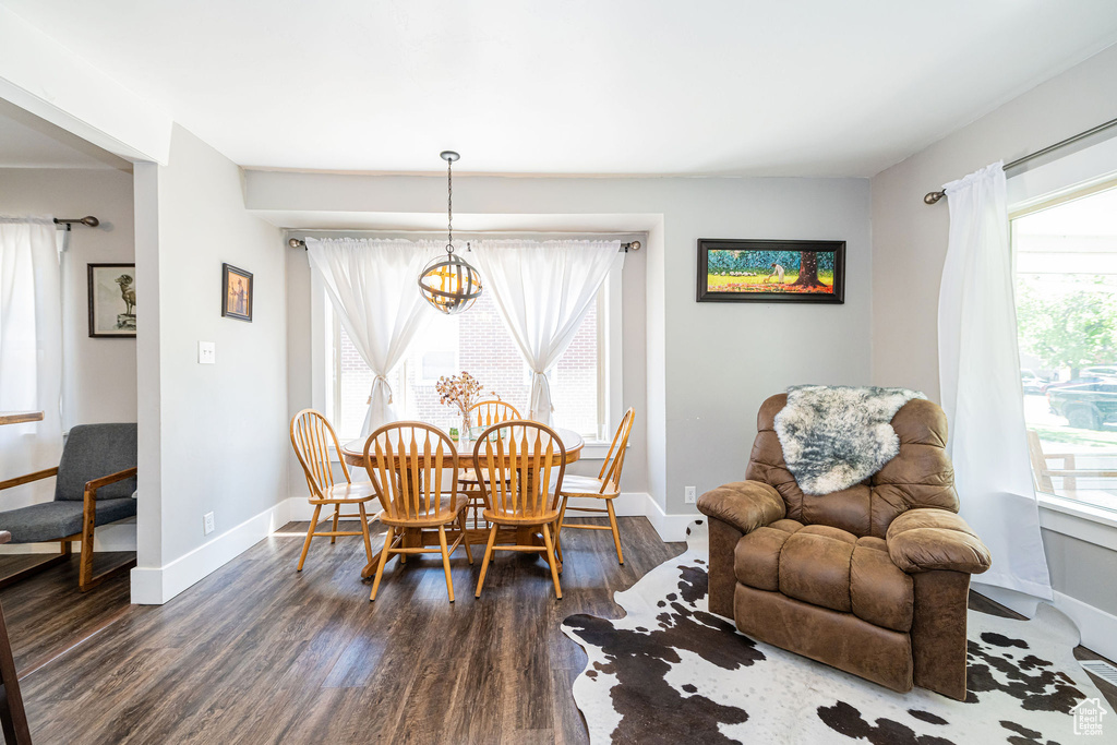 Dining area with dark wood-style floors, baseboards, and a chandelier