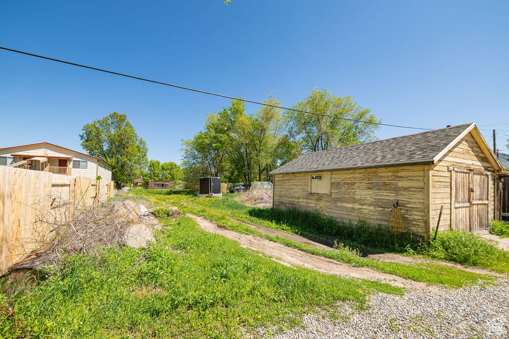 View of yard with a storage unit, an outbuilding, and fence