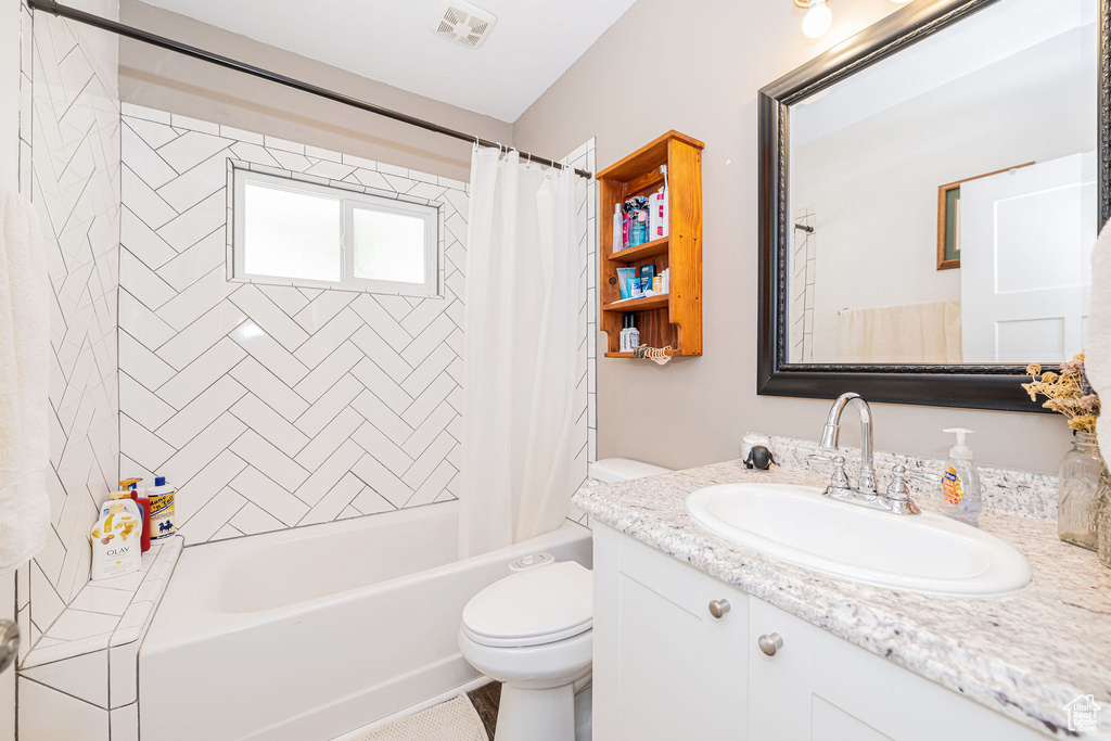 Bathroom with toilet, vanity, and shower / bath combo
