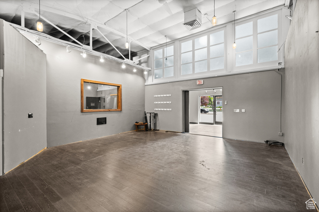 Unfurnished living room featuring wood finished floors, track lighting, and a towering ceiling