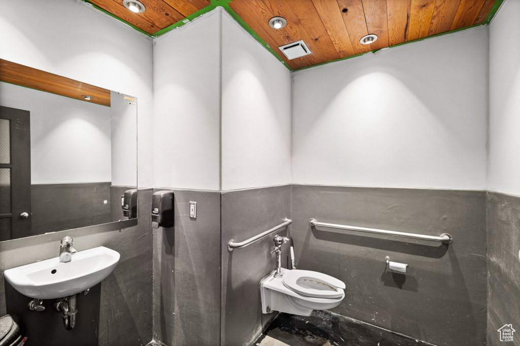 Half bath with a sink, wood ceiling, and toilet
