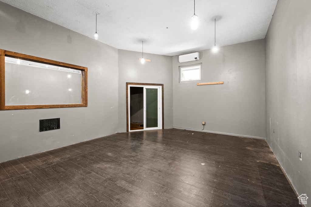 Empty room with a wall unit AC and wood finished floors