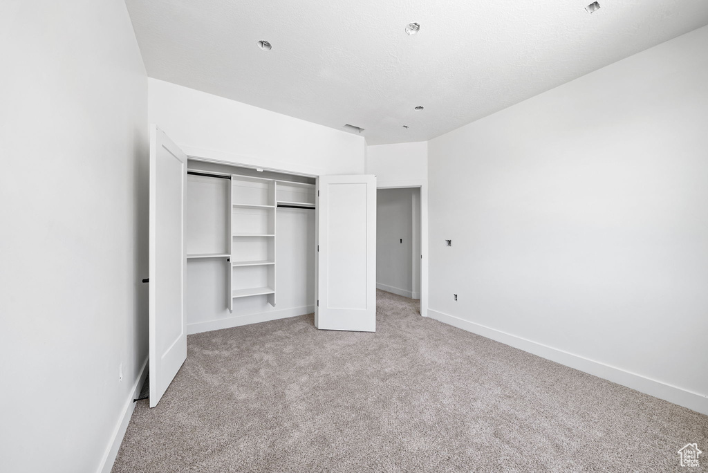 Unfurnished bedroom with light colored carpet and a closet