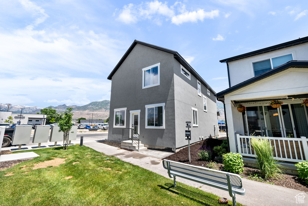 Back of property featuring a mountain view, stucco siding, and a lawn