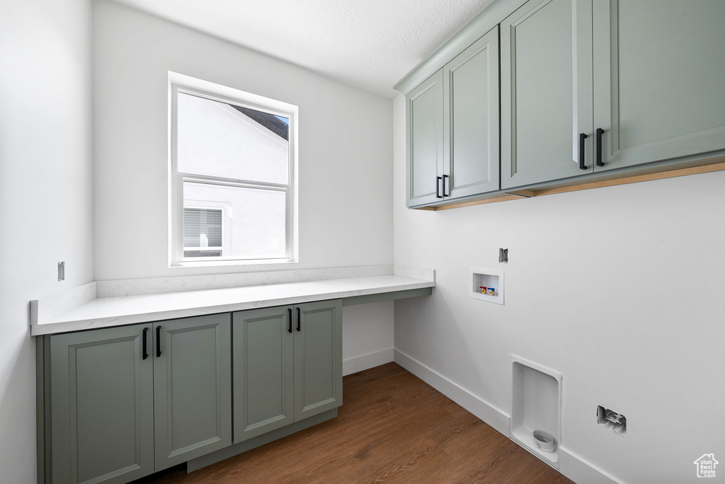 Washroom with cabinet space, hookup for a washing machine, wood finished floors, and an office area