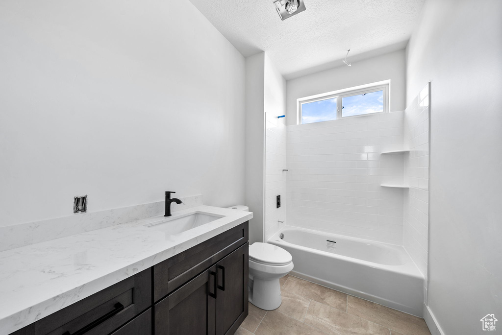 Full bath with vanity, a textured ceiling, and tub / shower combination