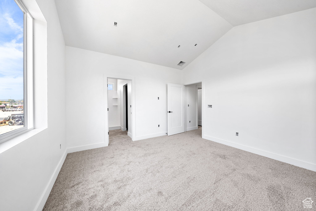 Unfurnished bedroom featuring vaulted ceiling and light carpet