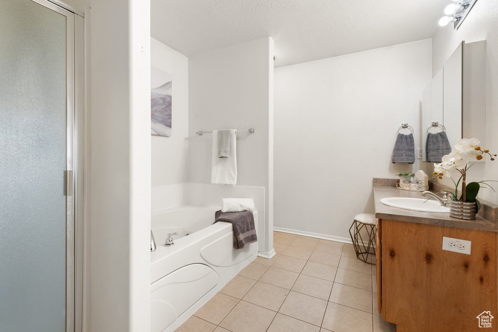 Full bathroom with tile patterned floors, a bath, vanity, a shower stall, and baseboards
