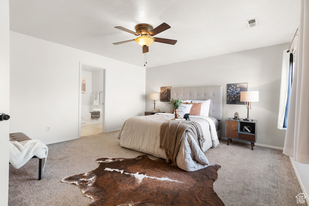 Bedroom featuring light carpet, baseboards, ensuite bath, and ceiling fan