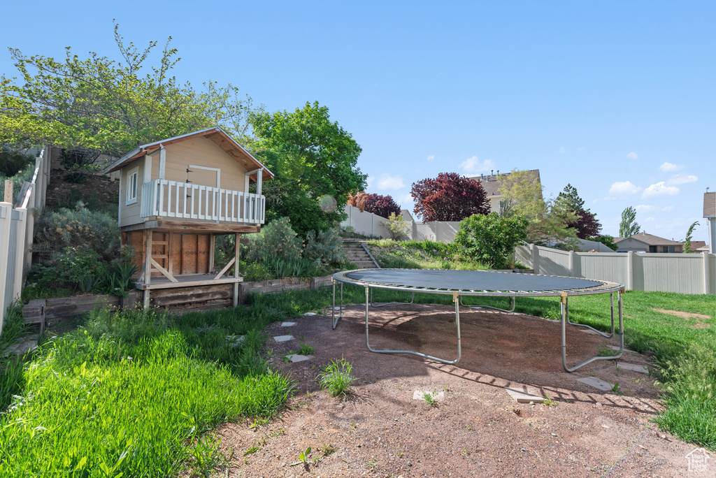 Fenced backyard featuring a trampoline