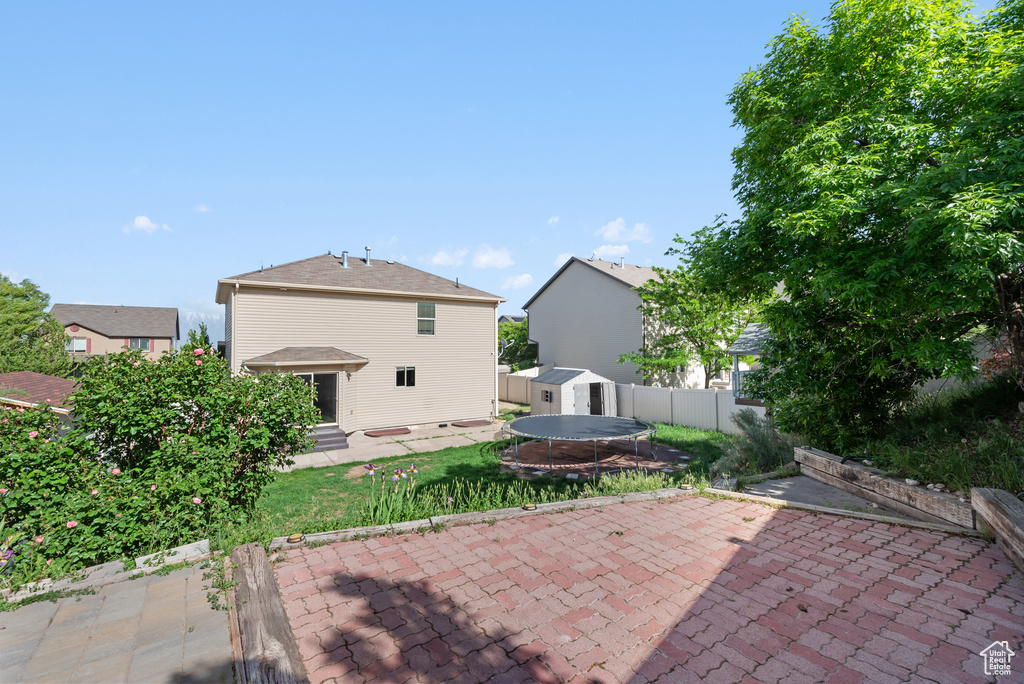 Rear view of house with a patio area, a storage shed, an outbuilding, and a fenced backyard