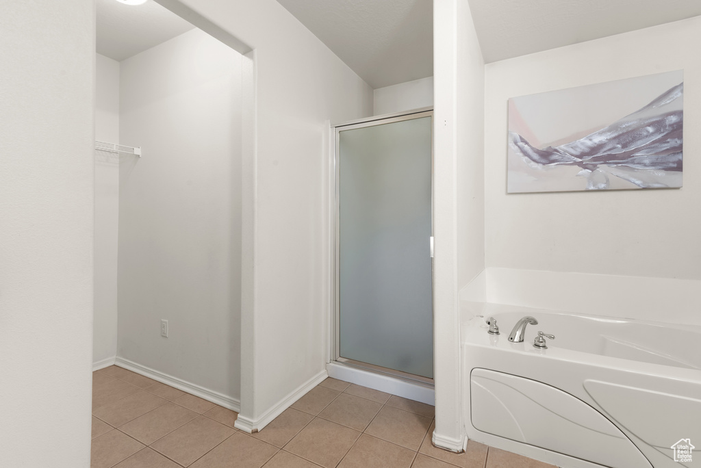 Bathroom featuring a shower stall, a garden tub, tile patterned flooring, and baseboards