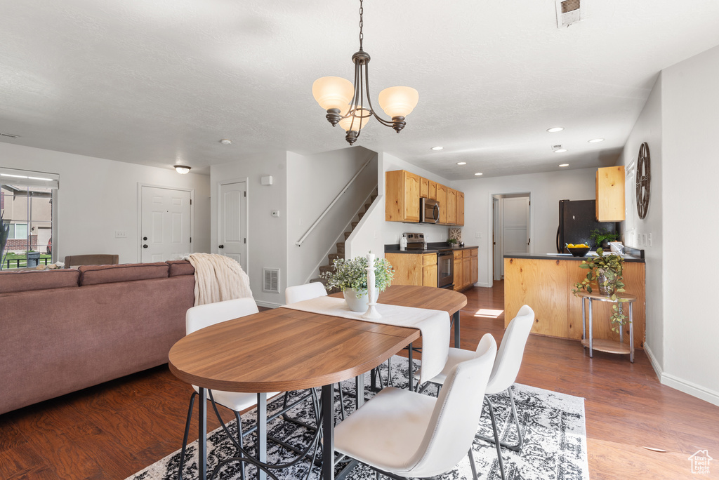 Dining area with stairway, wood finished floors, recessed lighting, a chandelier, and baseboards