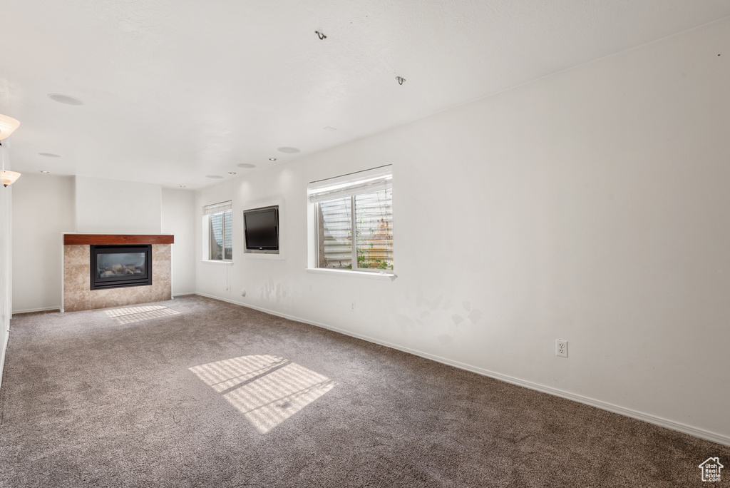 Unfurnished living room with carpet, baseboards, and a tiled fireplace
