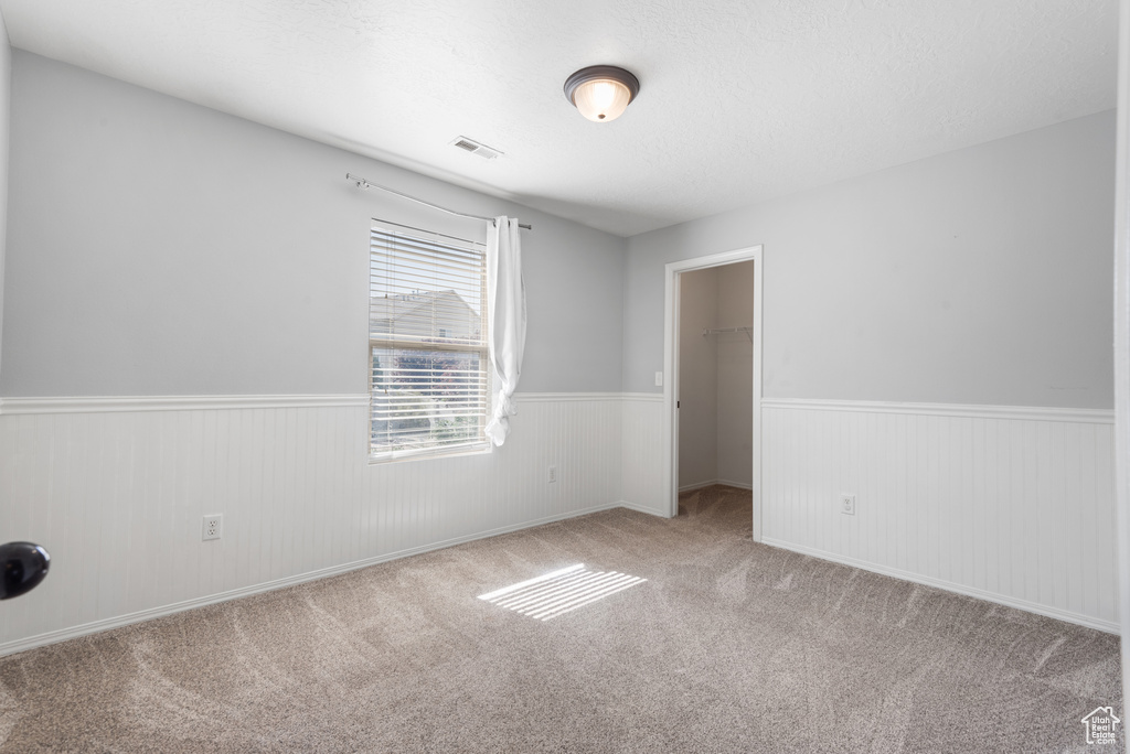 Carpeted spare room featuring wainscoting