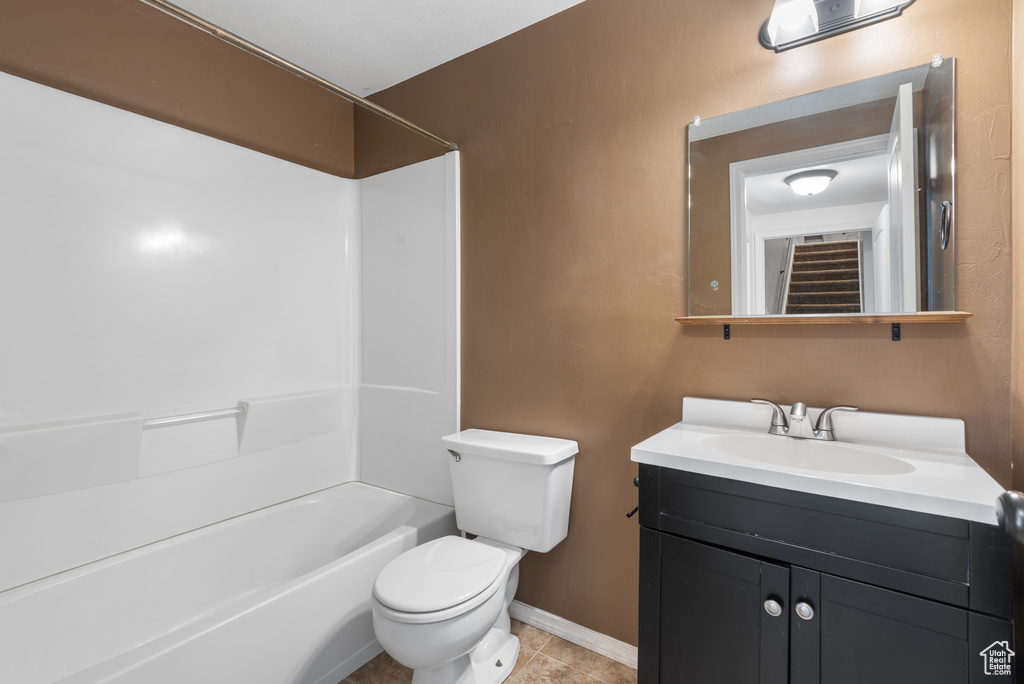 Bathroom with toilet, vanity, tile patterned flooring, baseboards, and shower / bath combination