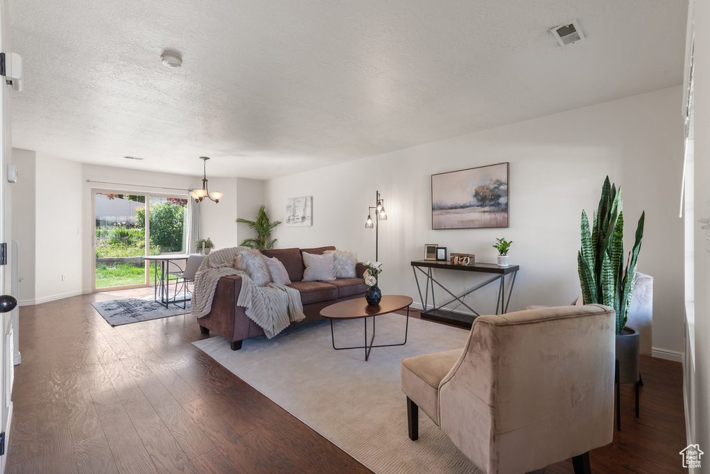 Living room with light wood-style floors, a chandelier, baseboards, and a textured ceiling