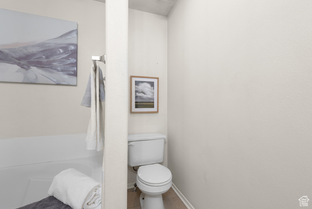 Bathroom featuring tile patterned floors, toilet, and baseboards