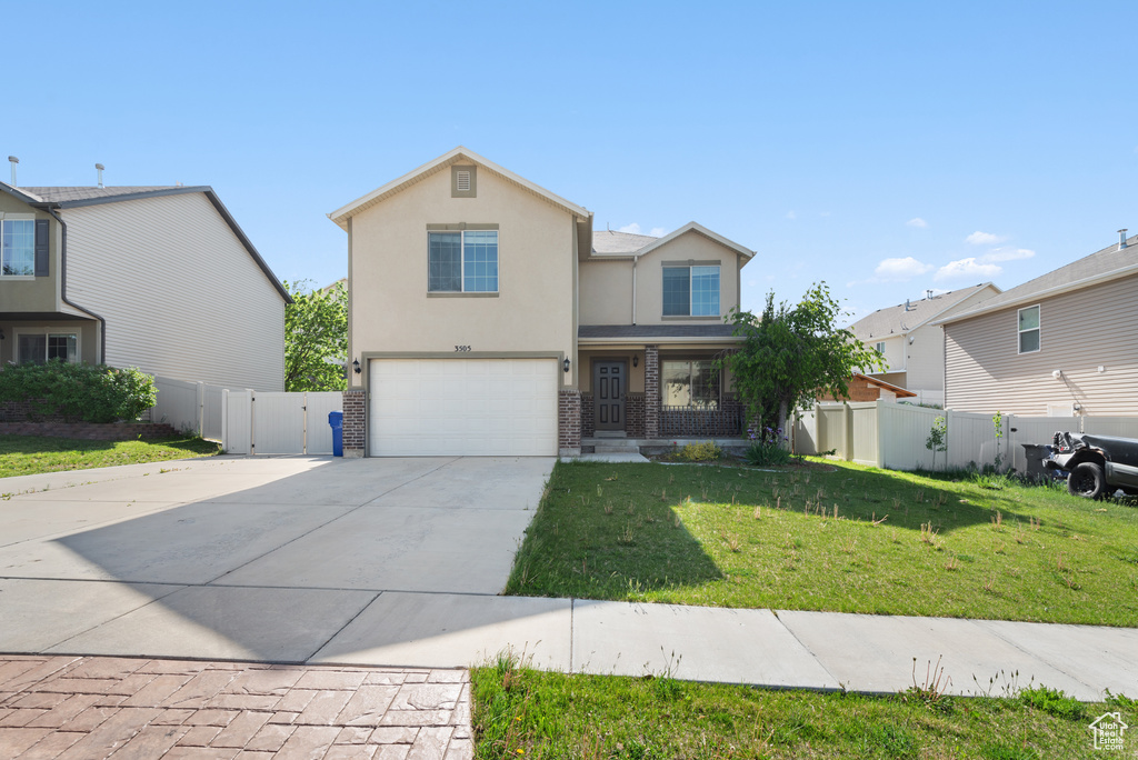 Traditional-style house with a gate, a garage, concrete driveway, brick siding, and stucco siding