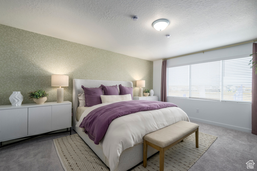 Bedroom featuring light colored carpet, a textured ceiling, and baseboards