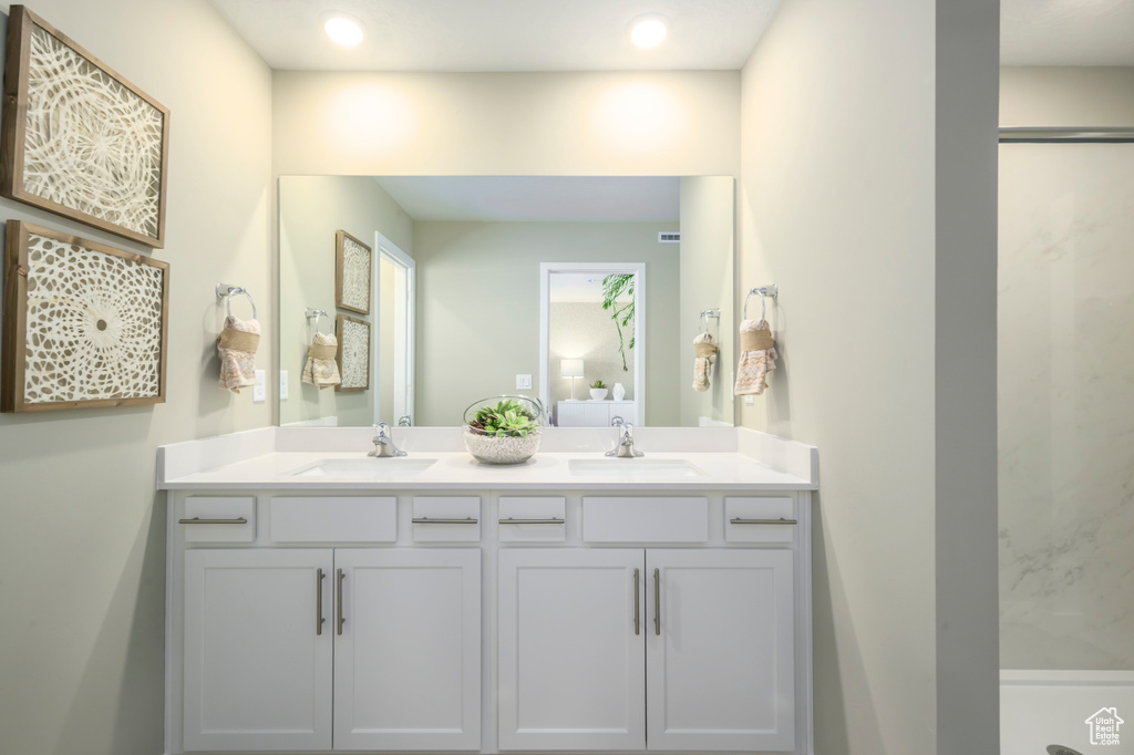 Bathroom with double vanity, a shower, and recessed lighting