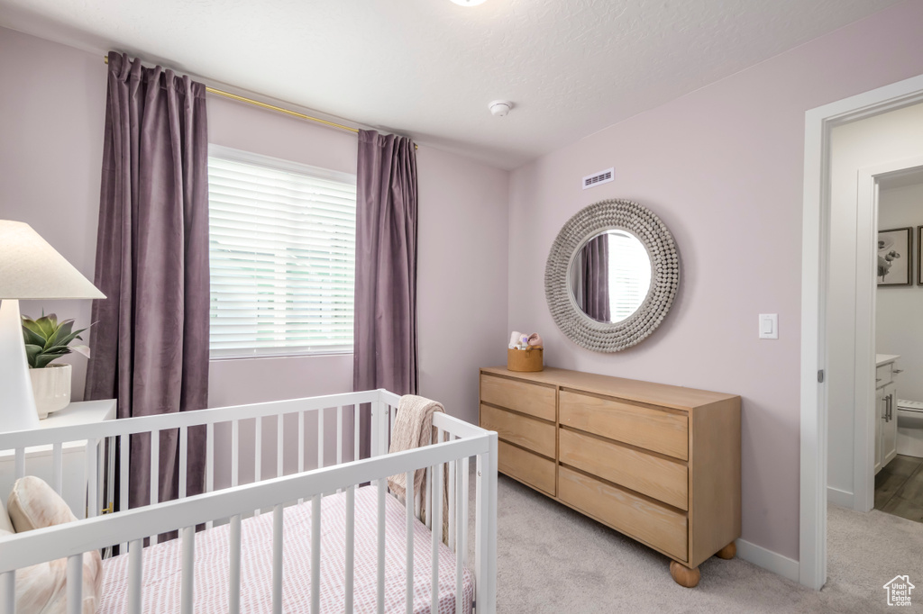 Bedroom with light carpet, baseboards, and a nursery area
