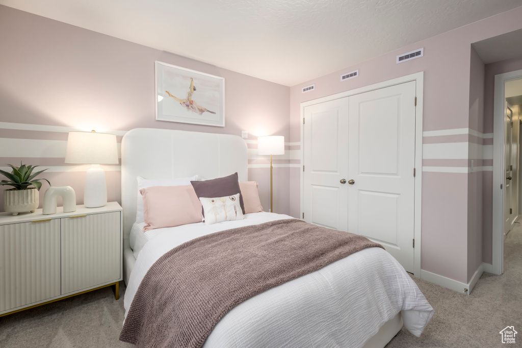 Bedroom featuring light carpet, a closet, and baseboards